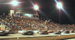 The NASCAR K&N Pro East Series cars zip past a packed main grandstand of the rain-delayed race. (Mike Lysakowski/ Motorsport Aspects)